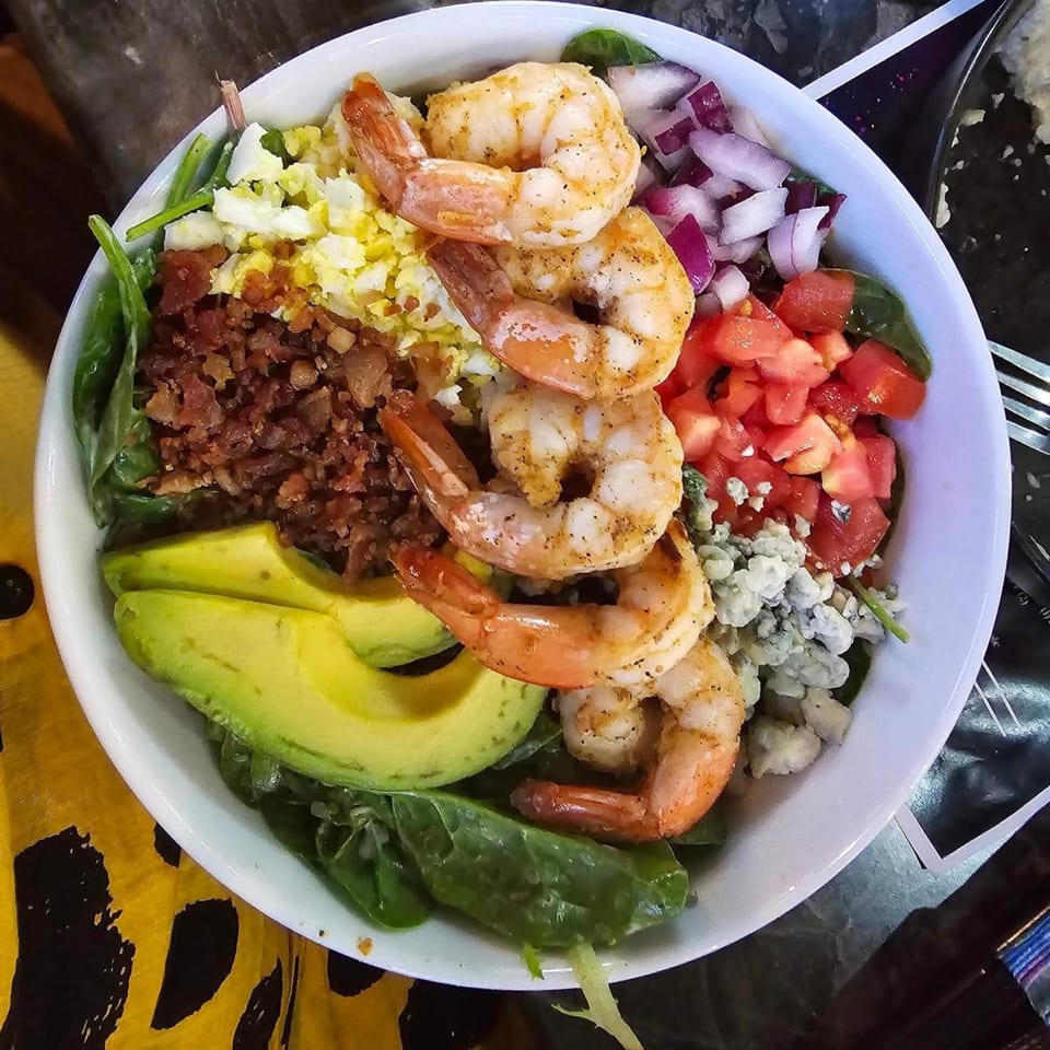 A vibrant Zodiac Bar & Grill shrimp salad with avocado, bacon, egg, tomato, and blue cheese.