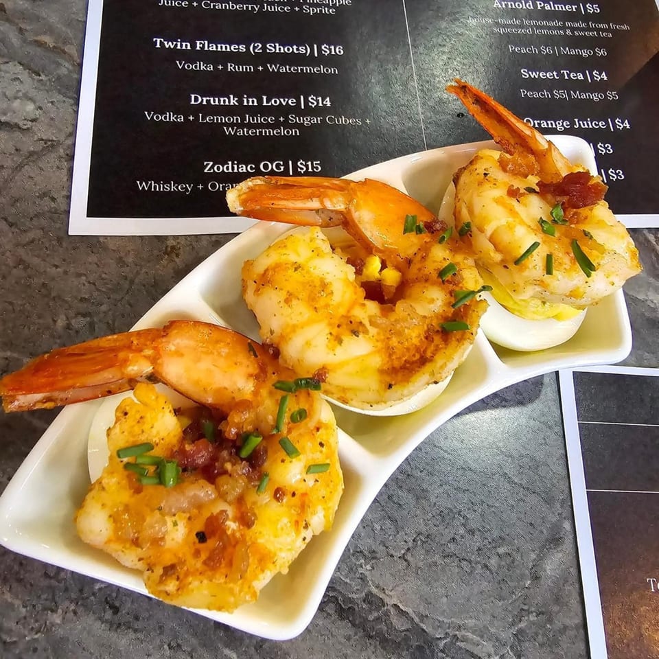 Three Zodiac Bar & Grill shrimp appetizers with bacon bits and chives on a white serving dish.